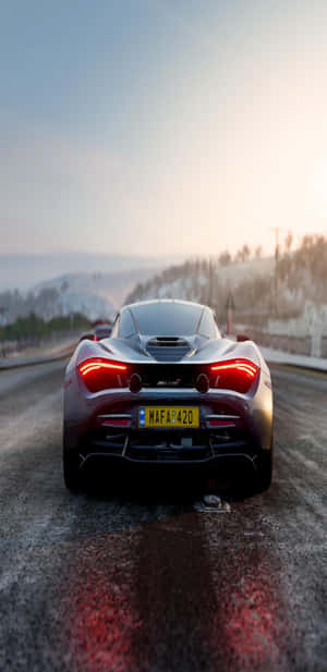 日落時分，銀色McLaren跑車在白雪覆蓋的山路上行駛。 — 麥拿侖 720S 壁紙
