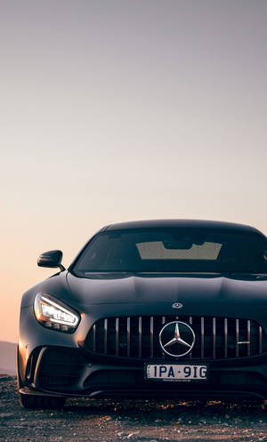 黑色 Mercedes-AMG GT 跑車停在夕陽下的礫石上