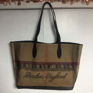 經典格紋Burberry托特包掛在牆上，上方有銅色閃片。 — 簡約美感 壁紙