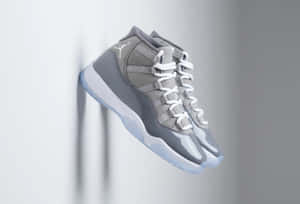 灰色Jordan 11運動鞋懸掛在半空中，背景為灰色牆壁。