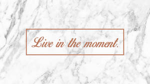 大理石背景，配以玫瑰金文字「live in the moment」。