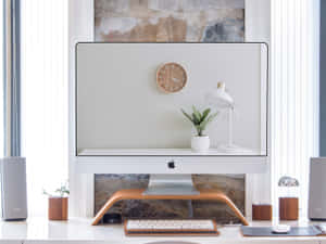簡約家居辦公室，配有iMac、植物和揚聲器靠近窗戶。
