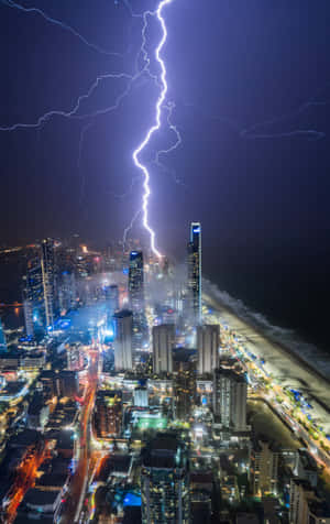 閃電照亮了夜晚的海岸城市，建築物閃閃發光，海灘燈火通明。 — 美麗的日落動畫 壁紙