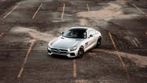 銀色 Mercedes-AMG GT 跑車停泊在一個風化的停車場。
