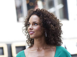 一位擁有捲髮和綠色上衣的女性在戶外向上看。 — 嘉麗姬莉 GIF 壁紙