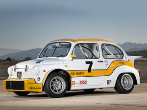 白色和黃色的Fiat Abarth賽車，編號7，在飛機跑道上。