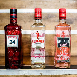 三瓶Beefeater氈酒陳列在金屬架上，背景是木頭。