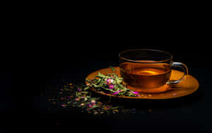 一個玻璃茶杯，裝有茶和乾燥的玫瑰花瓣，放在木製茶托上，背景為黑色。 — 青綠色 GIF 壁紙