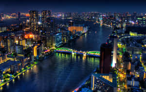 夜晚的城市，有燈火通明的建築物和水上亮燈的橋樑。 — 夜景城市 壁紙