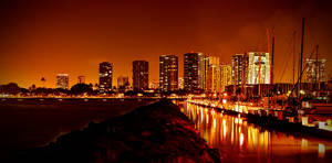 夜晚的城市天際線，閃爍的建築物和船隻倒映在水中。 — 夜晚 GIF 壁紙