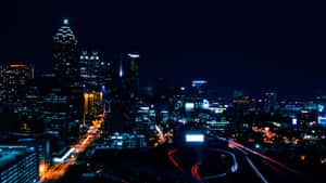 夜間城市天際線，有燈光建築和移動車輛的光跡。 — 夜景城市 壁紙