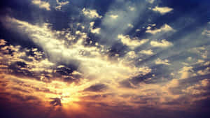 日落天空，金色光線穿透戲劇性的雲層。