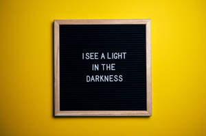黃色牆上帶有訊息 I SEE A LIGHT IN THE DARKNESS 的字母板