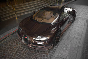 一輛棕色Bugatti跑車在夜晚停泊在鵝卵石街道上。 — 布加迪 壁紙