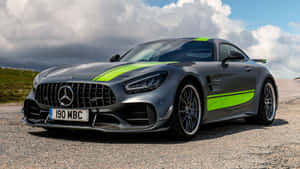 啞光灰色 Mercedes-AMG GT R 帶螢光綠色點綴，停泊在雲層下的碎石上。 — 汽車 壁紙