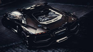 黑色林寶堅尼 Aventador 在夜間濕漉漉的鵝卵石街道上露出引擎。
