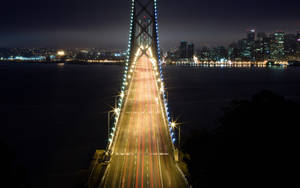 夜間的橋樑，帶有汽車燈光軌跡和背景的城市天際線。