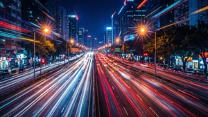 夜間城市高速公路，帶有流動的車燈光帶和高樓大廈。 — 城市景觀 壁紙