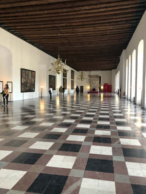 長長的博物館畫廊，棋盤格地板，參觀者正在觀看藝術品。