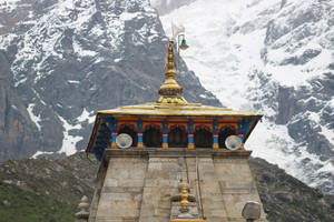一座金色屋頂、色彩繽紛拱門的寺廟，背景是白雪覆蓋的山脈。 — 廟宇 壁紙