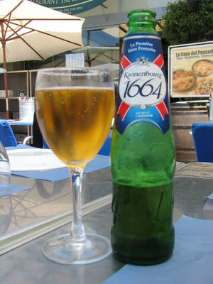 冰凍的Kronenbourg 1664啤酒瓶和玻璃杯在咖啡桌上。