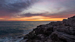 夕陽映照海洋，海浪拍打岩石海岸。 — 海浪 壁紙