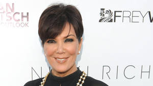 Kris Jenner 在活動中穿著黑色上衣和珍珠項鍊微笑。