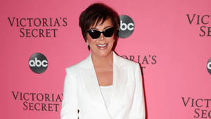 Kris Jenner 在Victoria's Secret活動中戴著太陽眼鏡和白色西裝外套。