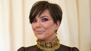Kris Jenner 戴住金色寶石頸鏈對住鏡頭微笑