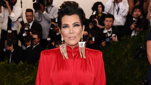 Kris Jenner 身穿紅色禮服在紅地毯活動中為相機擺姿勢。