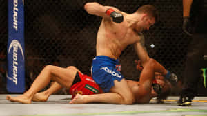 兩名MMA拳手在UFC八角籠內纏鬥，其中一人發出肘擊。 — 運動 壁紙