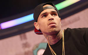 Chris Brown 戴住黑色帽同金鏈喺台上向上望。 — 基斯洛克 GIF 壁紙