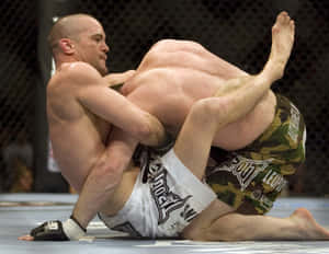 兩名男性MMA拳手在八角形內的藍色墊子上鎖定纏抱姿勢。