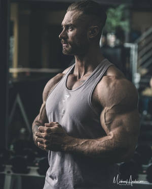 運動型男人，肌肉線條分明，在健身房穿著灰色背心站立