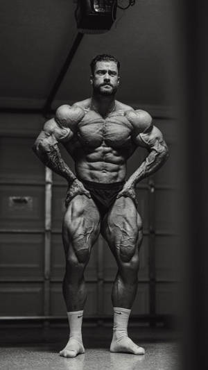 一位肌肉發達的男子在健身房中擺姿勢，擁有清晰的肌肉和紋身。