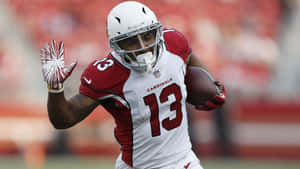 身穿 Cardinals 球衣的足球員持球奔跑並揮手。