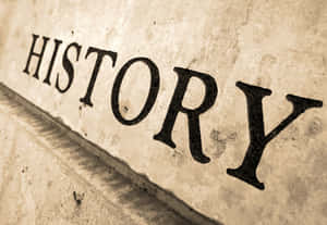 「HISTORY」一詞的特寫，雕刻在帶有紋理表面的舊石上。
