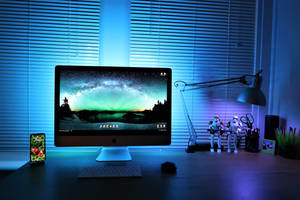 一張發藍光的桌子，上面有顯示極光壁紙的 iMac 和暴風兵人偶。