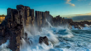暮色中，海浪衝擊玄武岩岩層。