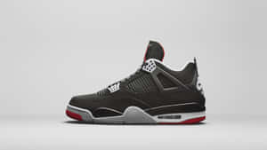 黑色 Jordan 4 運動鞋，帶有紅色和銀色細節，置於灰色背景上。