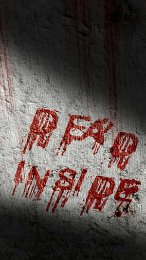 在聚光燈下粗糙的混凝土牆上，血紅色塗鴉寫著 fear inside。