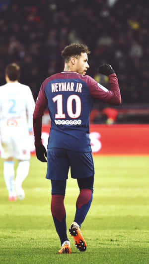 足球員尼馬（Neymar Jr）在燈光明亮的體育場上身穿藍色和栗色球衣慶祝。
