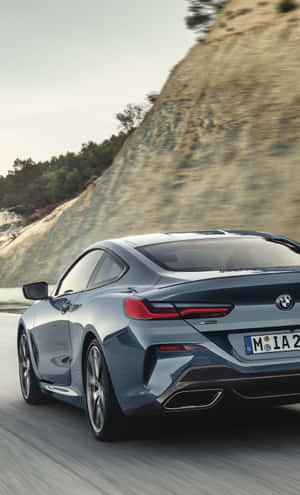 藍色BMW 8系轎跑車在日落時分的山路上奔馳