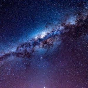 銀河系在黑暗的夜空中閃耀著藍色和紫色的星星。