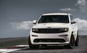 多雲天空下，賽道上帶有紅色和白色路緣石的白色Jeep SUV。
