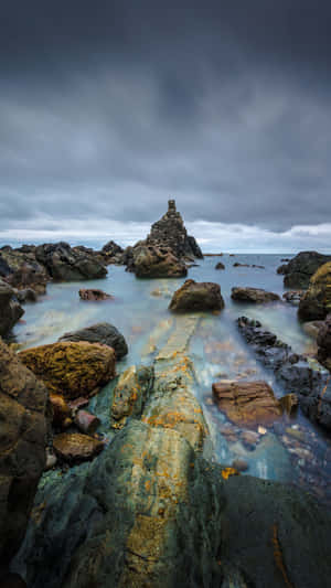 崎嶇的海岸岩石，在暴風雨的天空下，光滑的水流流過。