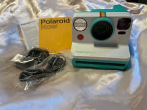 青綠色和白色的Polaroid Now相機連配件，置於銀色緞面上。