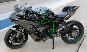 黑色和綠色 Kawasaki Ninja 運動電單車在賽道表面上。