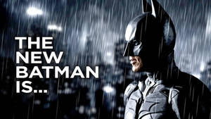 蝙蝠俠在雨中，身後有城市燈光和文字「THE NEW BATMAN IS...」。