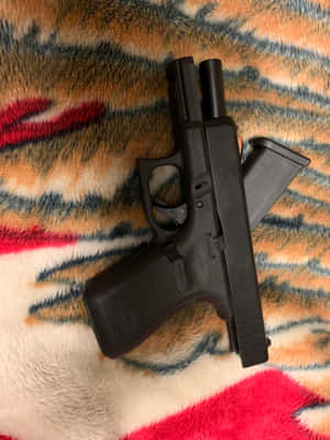 黑色手槍和彈匣放在一條色彩繽紛、毛茸茸的毯子上。 — Glock GIF 壁紙